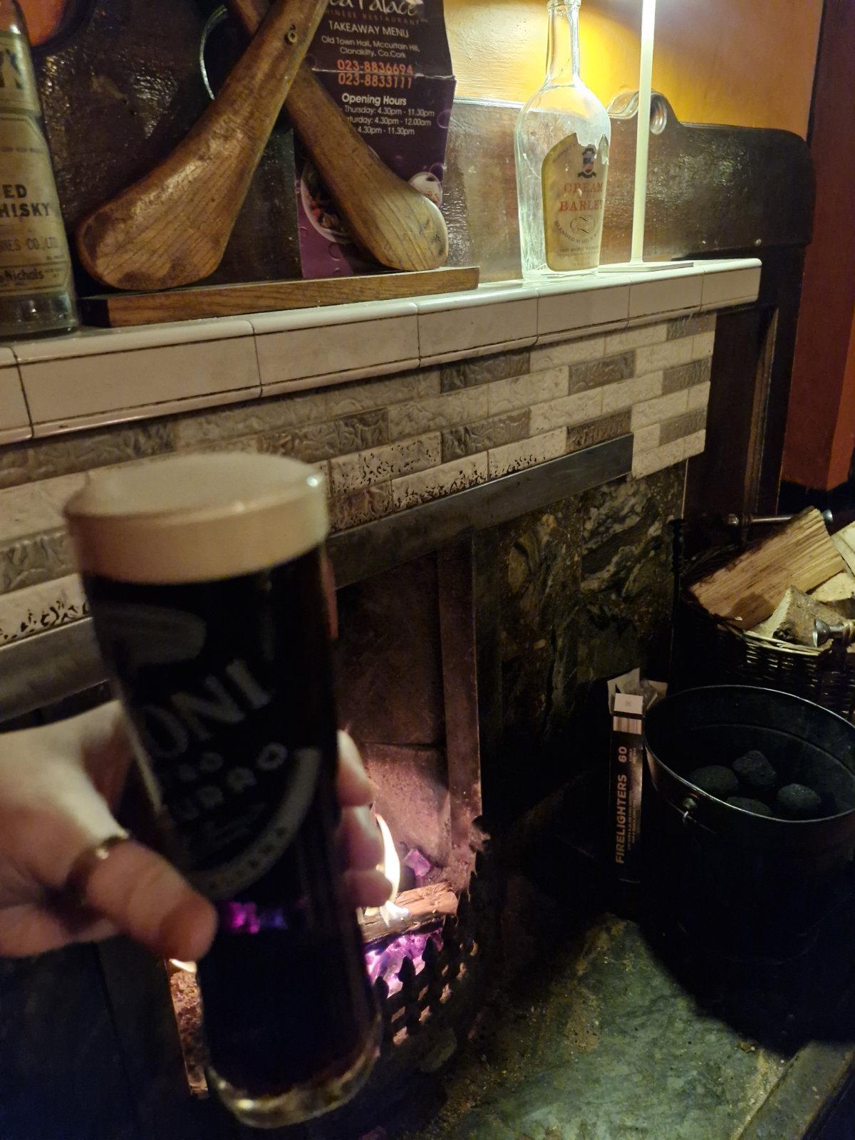 Guinness beside a real fire in a pub in clonakilty